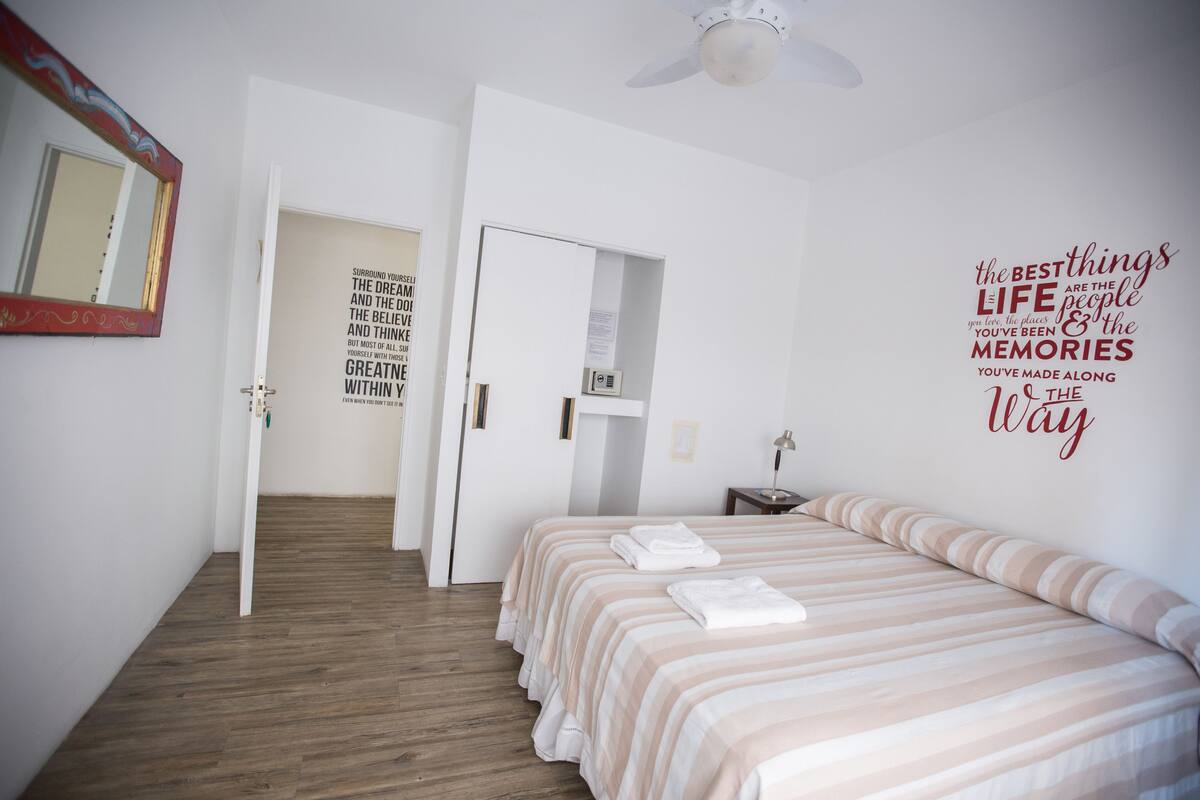 A hotel room with a bed, a ceiling fan, and motivational wall art.
