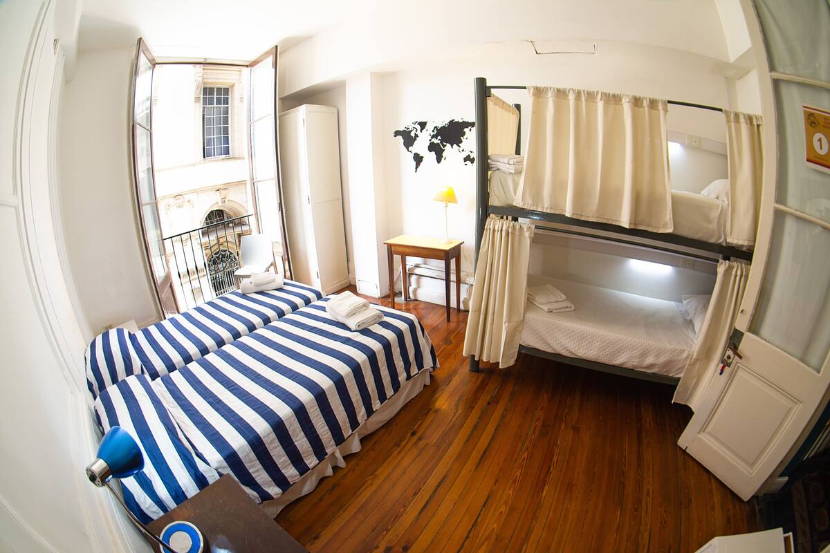 A compact room with two beds, a small table, and a lamp.