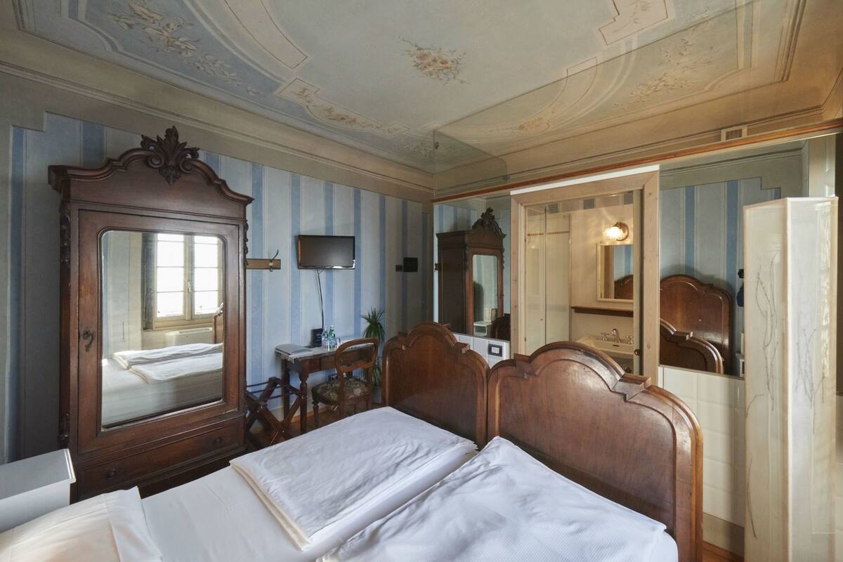 Une chambre à coucher avec un grand miroir, un lit en bois, un bureau et une télévision.