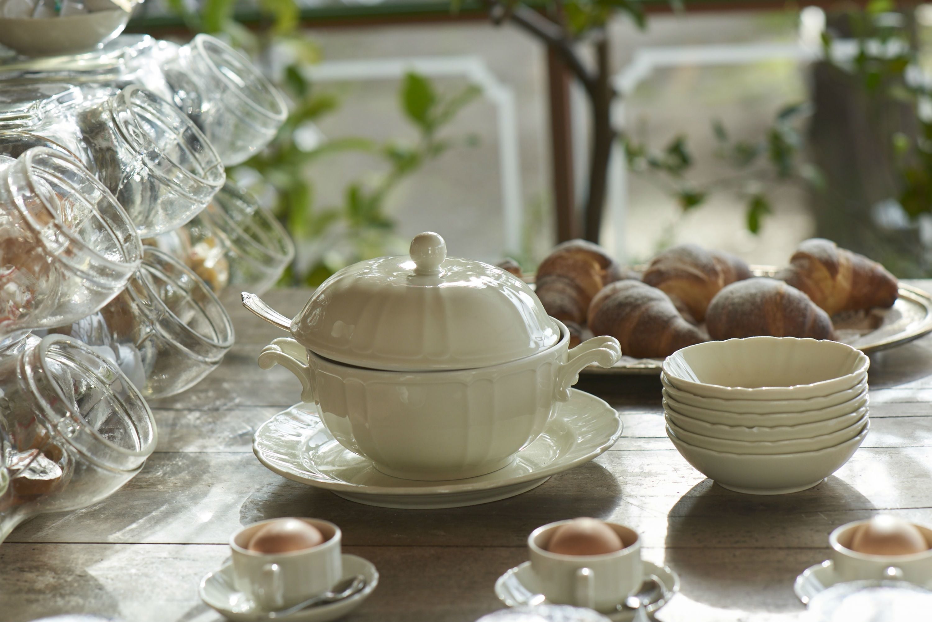 Una mesa dispuesta con una tetera blanca, tazas de té y pasteles.