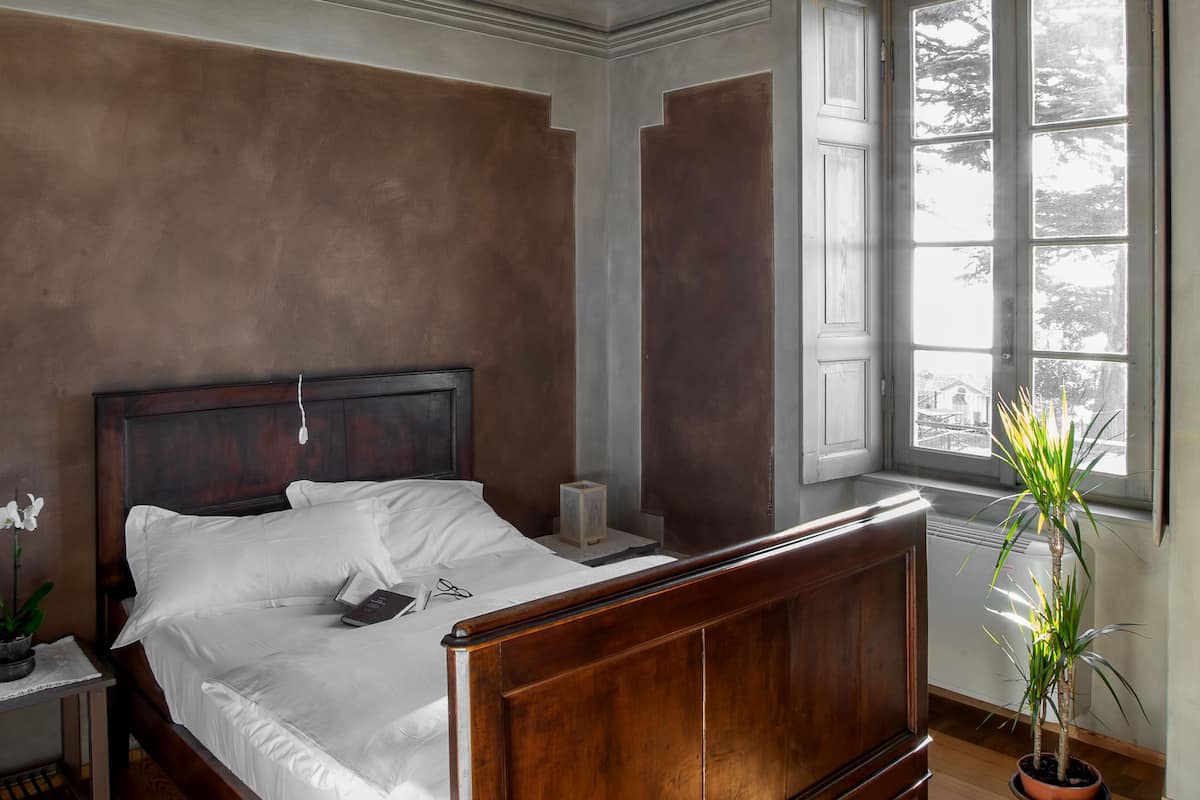 Une chambre à coucher avec un lit en bois, une table de chevet, une plante en pot et une fenêtre donnant sur un beau paysage.
