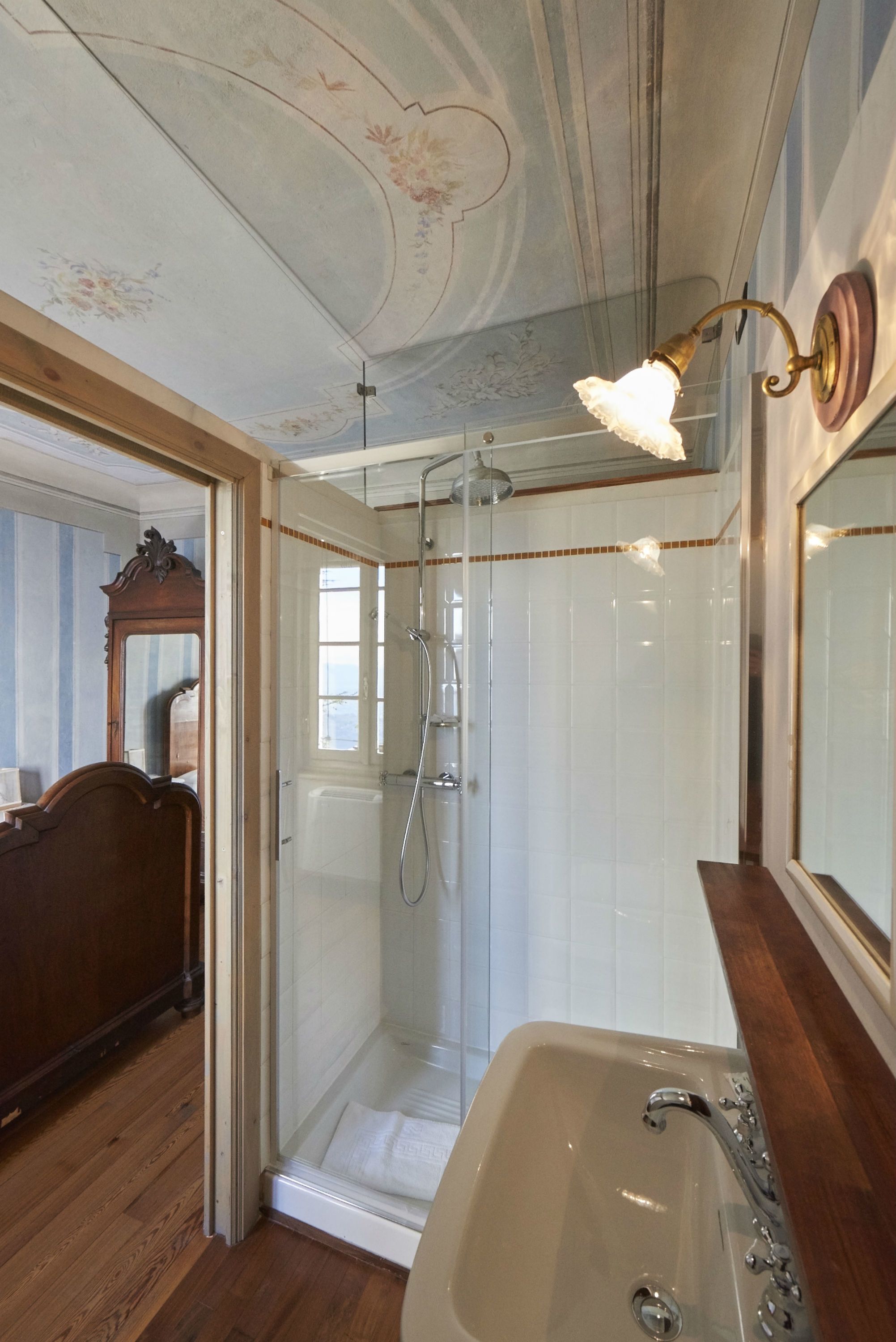 Une salle de bain dotée d’une douche à parois de verre, d’un meuble-lavabo en bois et d’un grand miroir.