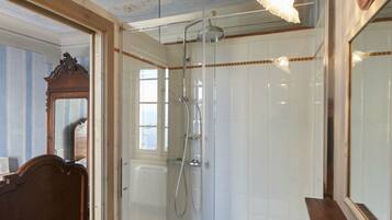 A bathroom with a glass-enclosed shower, a wooden vanity, and a large mirror.
