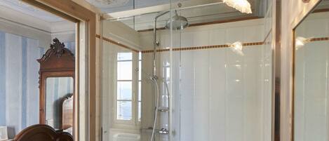 Une salle de bain dotée d’une douche à parois de verre, d’un meuble-lavabo en bois et d’un grand miroir.