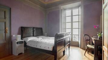 Ein Schlafzimmer mit einem Holzbett, einem Nachttisch, einem Sessel und einem Fenster mit Blick.