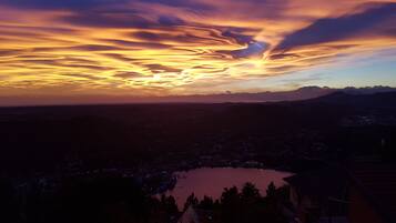 A panoramic view of a city at dusk with a lake and mountains in the background.