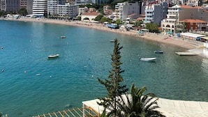 A coastal town with buildings, a beach, and boats. - New Hotel Kuc By Marvel (Becici)
