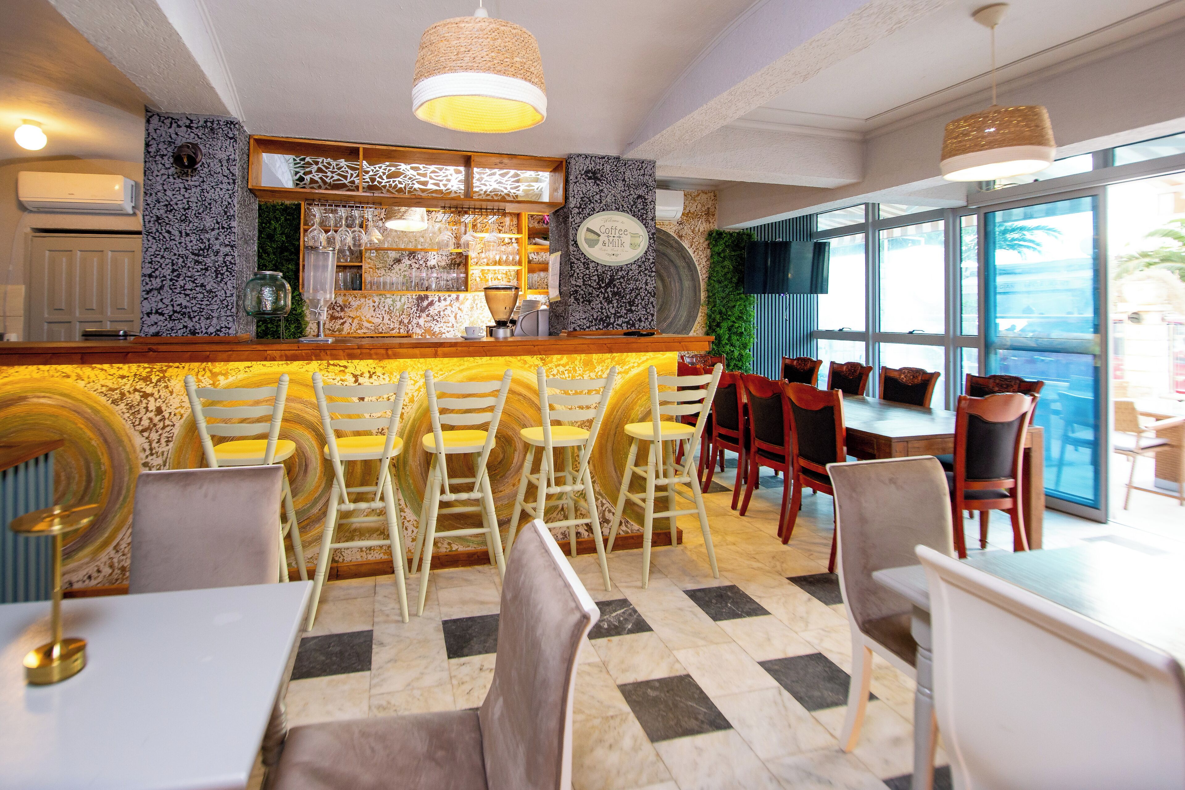 Uma área de bar com balcão, banquetes e um espaço de estar com mesas e cadeiras.