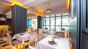A dining area with tables set for two, featuring white tablecloths and modern chairs. - New Hotel Kuc By Marvel (Becici)