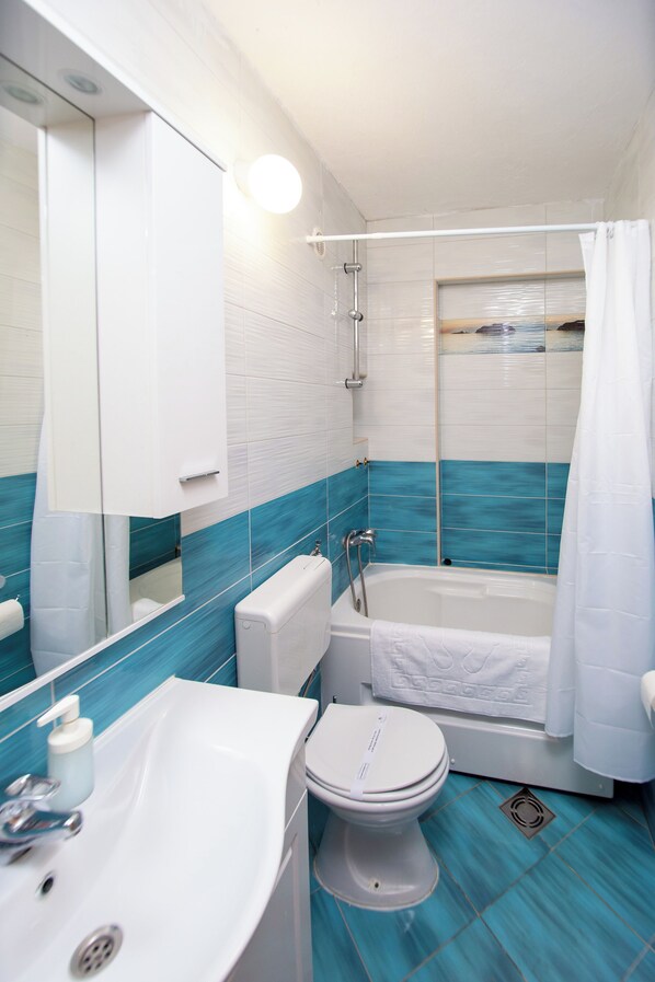 Une salle de bain avec une baignoire, des toilettes, un lavabo et un miroir.