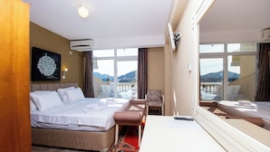 A hotel room with a bed, a chair, a desk, and a large window offering a mountain view. - New Hotel Kuc By Marvel (Becici)