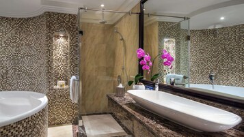 Un baño moderno con una bañera independiente grande, una ducha a pie y un tocador con un espejo amplio.