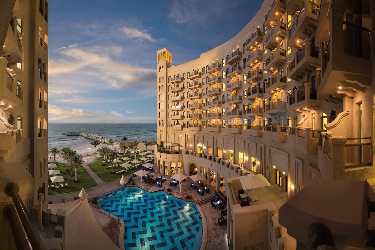 A hotel with a pool, outdoor seating, and a view of the ocean.