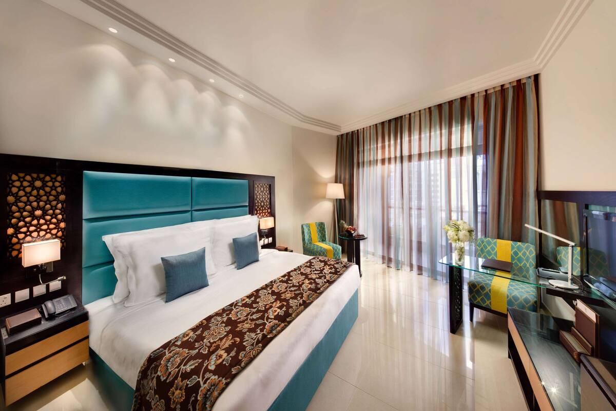 Una habitación de hotel moderna con una cama grande, un televisor de vidrio y un balcón con cortinas.