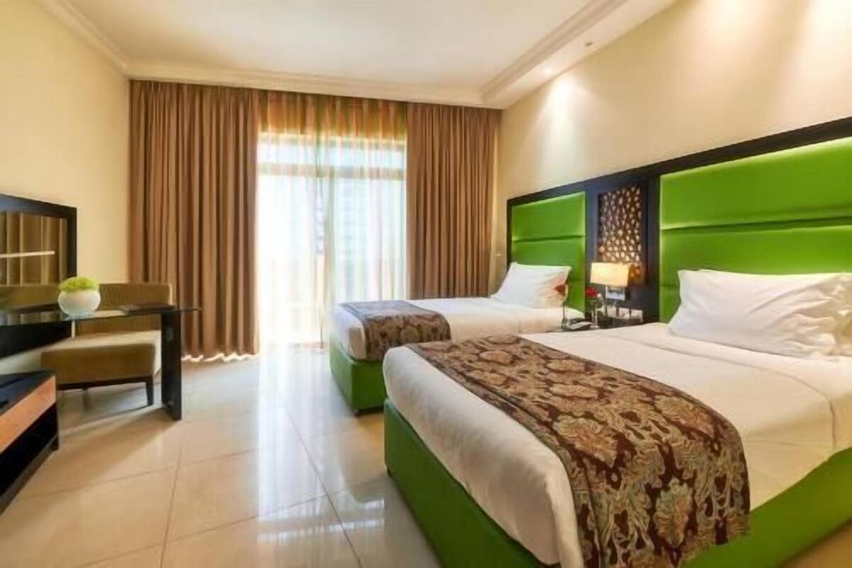 Habitación de hotel con dos camas, un escritorio, una silla y un televisor.