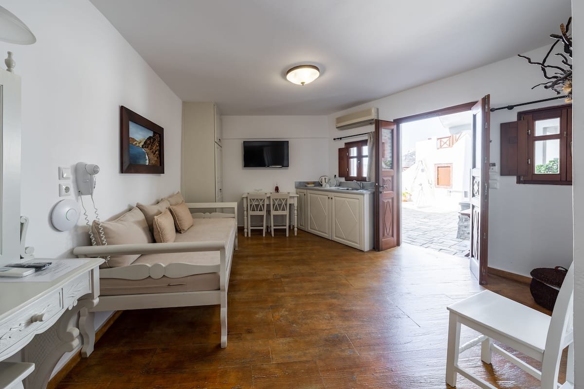 Una habitación acogedora con un sofá blanco, una mesa de comedor y una zona de cocina con televisor.