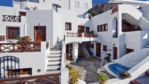 A white building with a pool and outdoor seating. - Smaro Studios (Santorini)