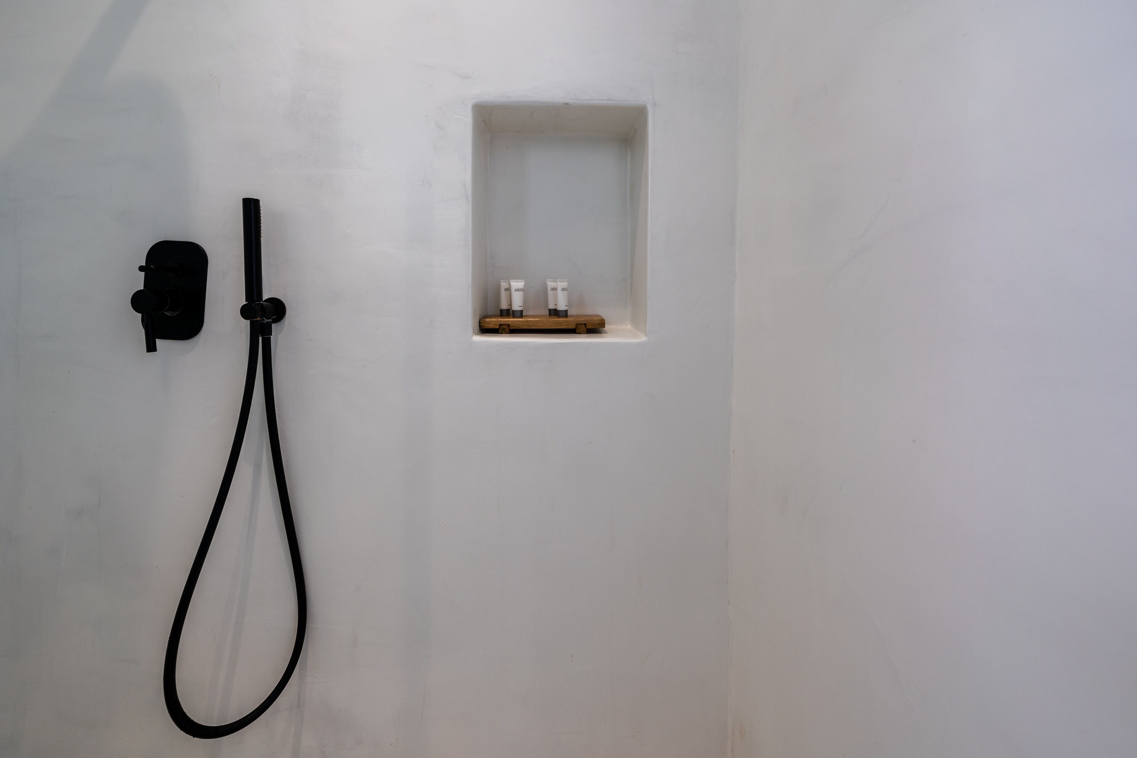 Une salle de bain minimaliste avec une douche, un porte-savon et un porte-serviettes.