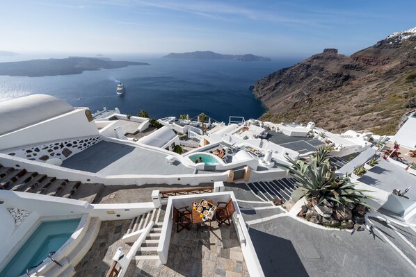 A rooftop terrace with a pool, dining area, and a view of the sea and mountains. - Smaro Studios (Santorini)