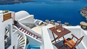 A hotel with a pool, outdoor seating, and a view of the sea. - Smaro Studios (Santorini)