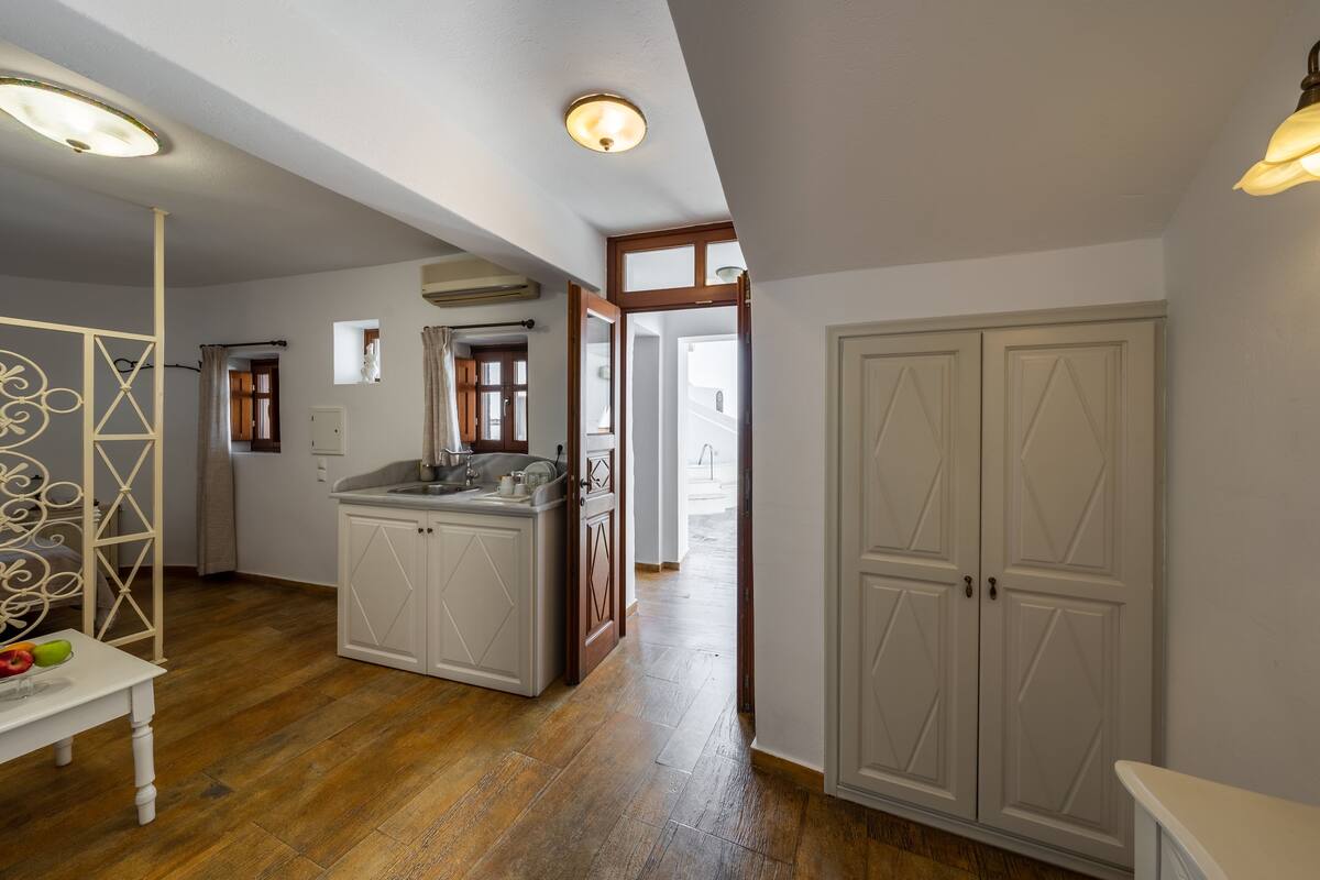 Una cocina amplia con piso de madera, muebles de cocina blancos y una isla central.