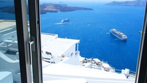 A view from a high-rise building overlooking a coastal area with two cruise ships in the sea. - Smaro Studios (Santorini)
