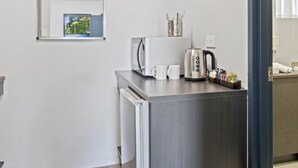 A kitchenette with a microwave, kettle, and coffee maker, along with a small coffee station. - Grafton Central Motel (Grafton)