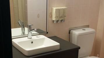 A bathroom with a white sink, dark cabinets, a toilet, and a mirror.
