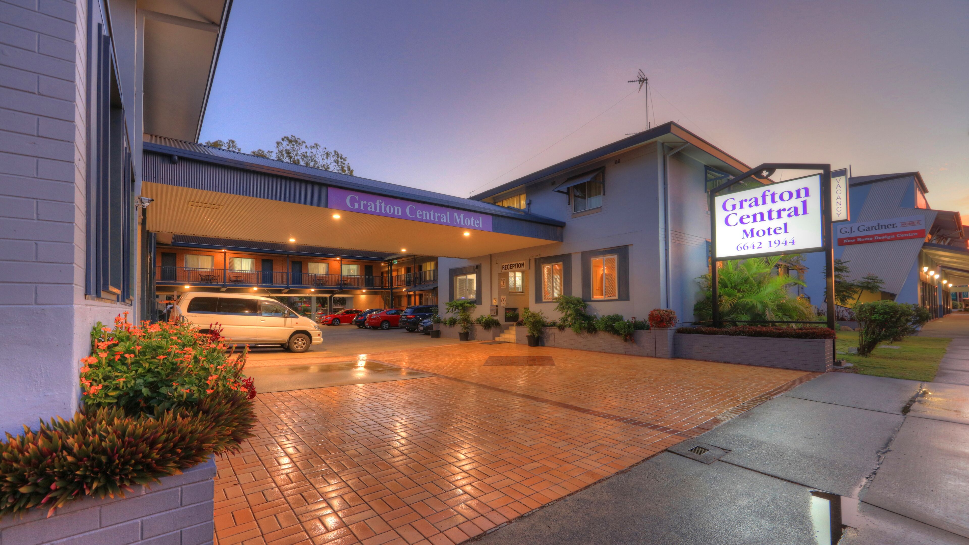 The Grafton Central Motel with a brick entrance, a reception area, and a parking lot with several cars.