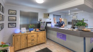 A reception desk with a sign reading "Grafton Central Hotel," a coffee machine, a potted plant, and framed pictures on the wall. - Grafton Central Motel (Grafton)