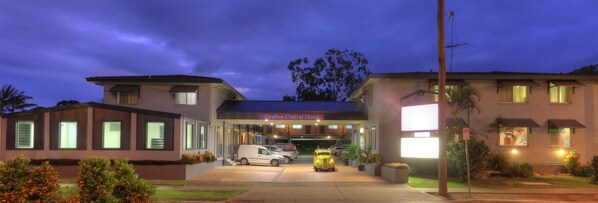A motel with a covered entrance, a parking area with several vehicles, and a well-lit facade.