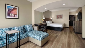 Una habitación de hotel con sofá, cama, escritorio y televisor.