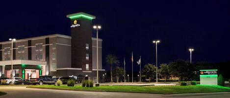 A hotel with a prominent tower, multiple parking spaces, and a well-lit entrance.