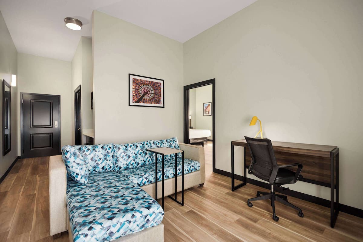 A modern living room with a sectional sofa, a small table, a desk with a chair, and a large mirror.
