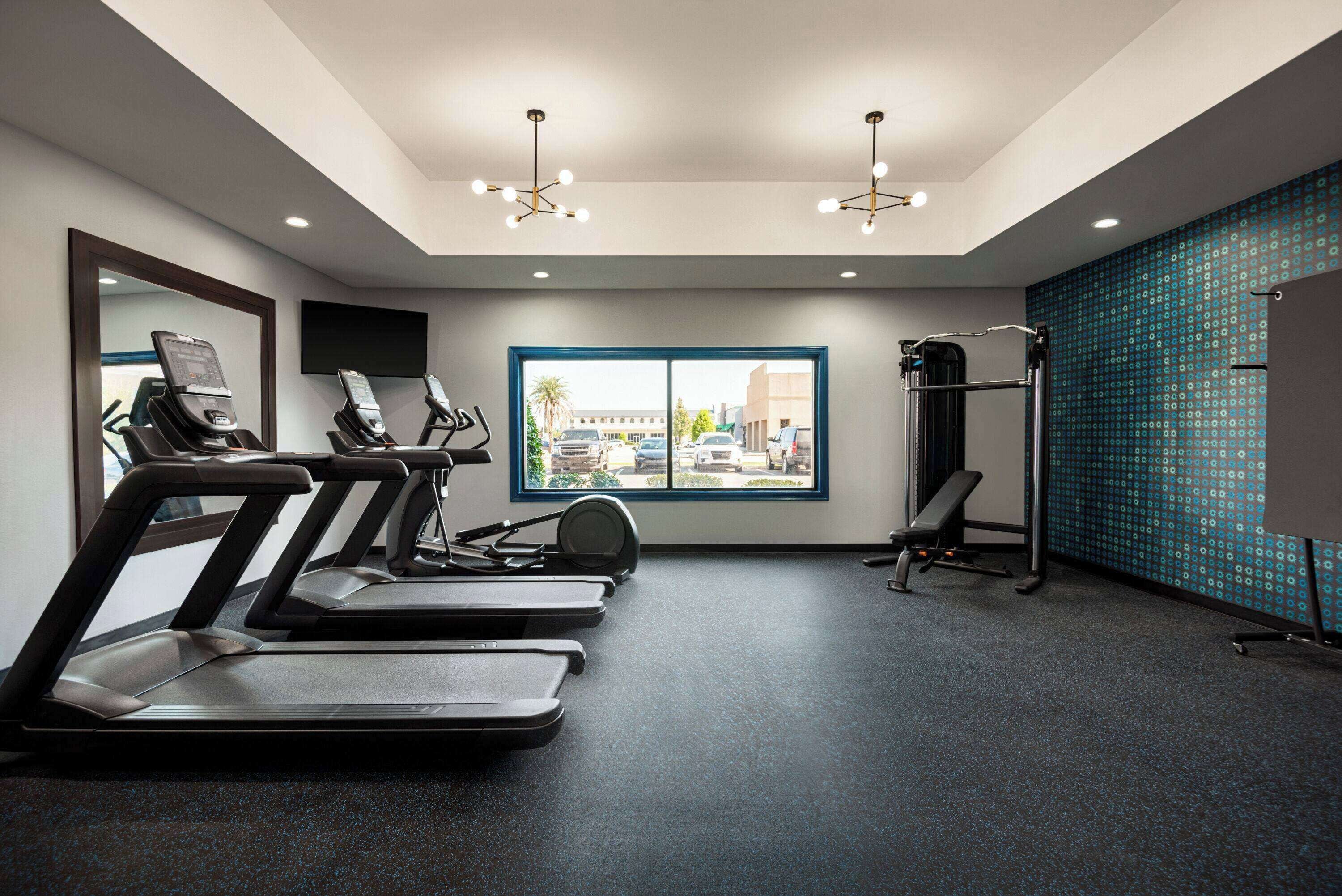 A gym with treadmills, a stationary bike, and a bench.