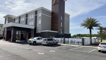 A modern hotel with a prominent tower, multiple parking spaces, and a gated entrance.