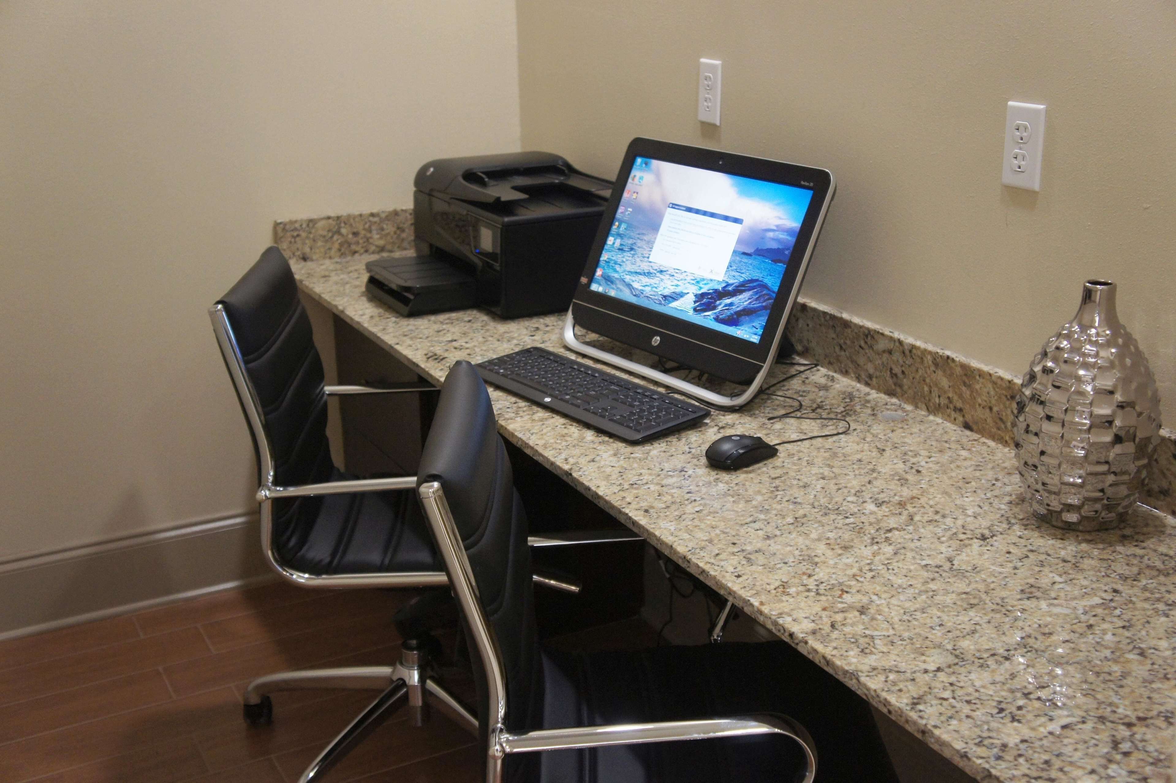 A conference room with a granite countertop, a laptop, a printer, two chairs, and a decorative vase.