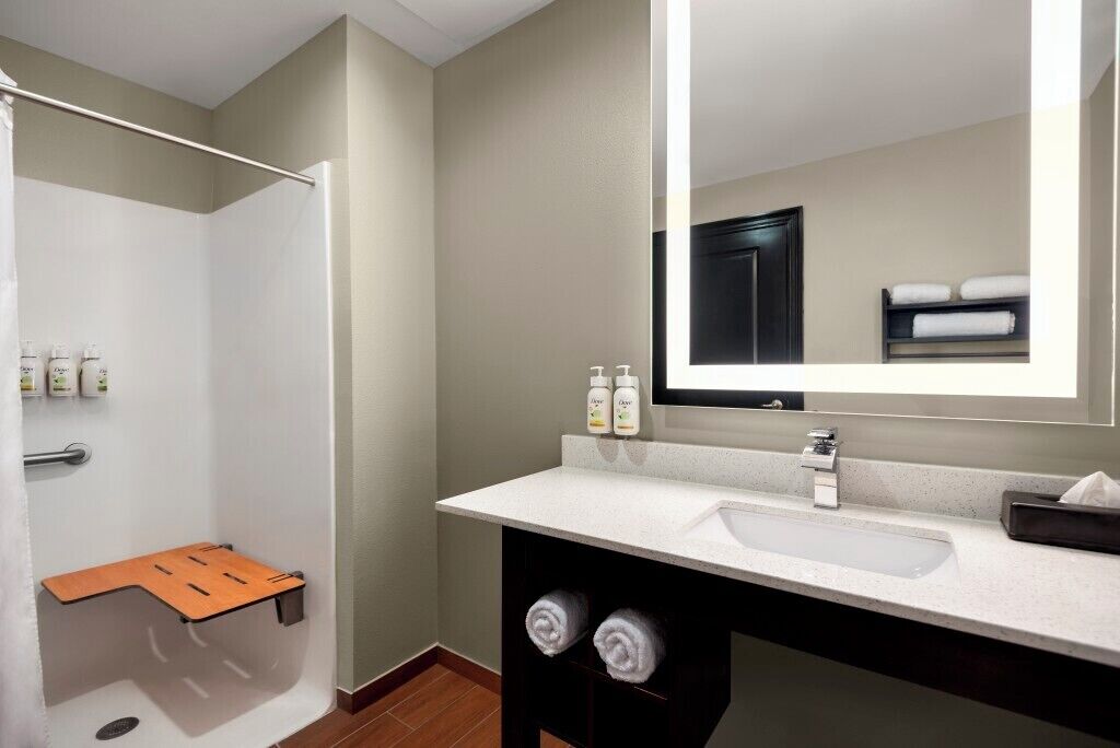 A modern bathroom with a shower, a sink, a mirror, and a towel rack.