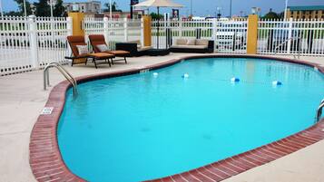 Relax by the pool surrounded by a picket fence and lounge chairs.