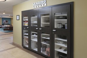 UN LOCKER DE PRESTAMO con varios compartimentos para almacenamiento, situado en un pasillo con piso de baldosas y una zona de estar al fondo.