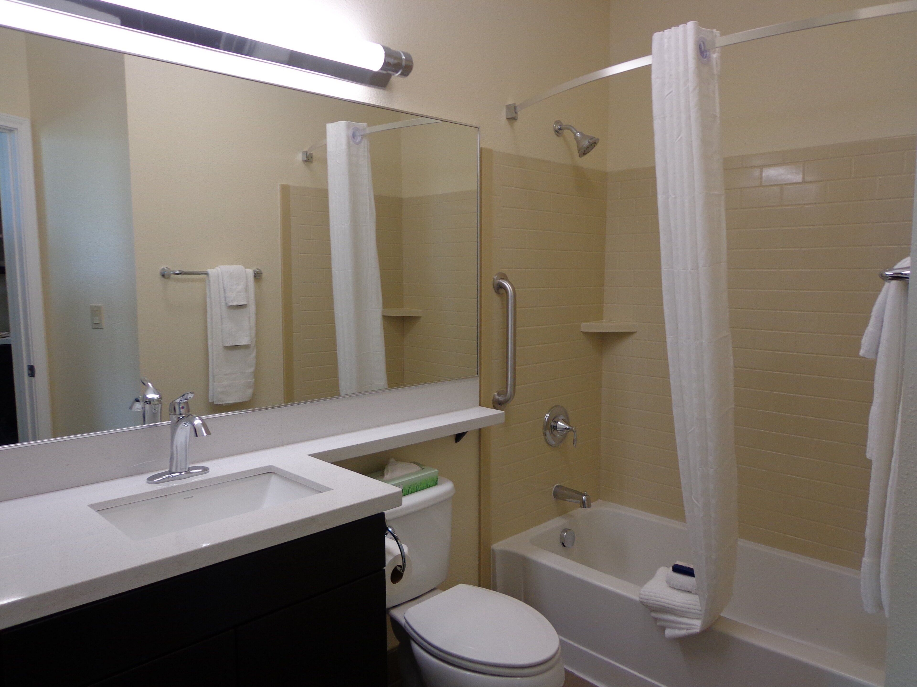 A bathroom with a toilet, sink, mirror, shower, and bathtub.