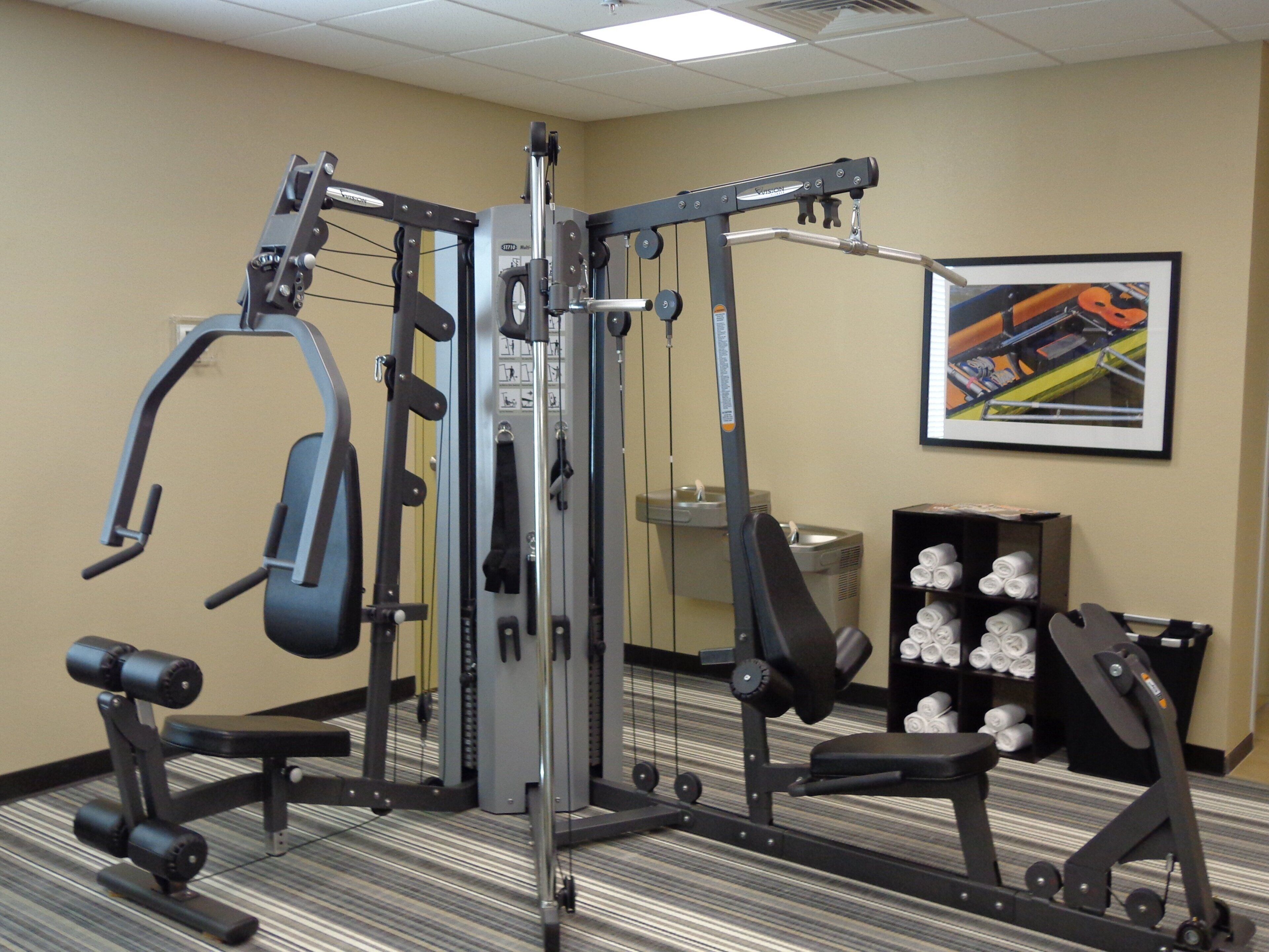 A gym with various exercise equipment, a wall-mounted picture, and a shelf with rolled towels.