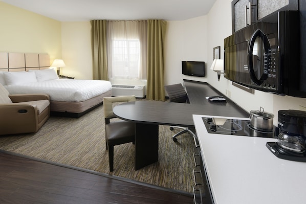 Une chambre d’hôtel équipée d’un lit, d’un canapé, d’une table à manger, d’une télévision, d’un four à micro-ondes et d’une machine à café.