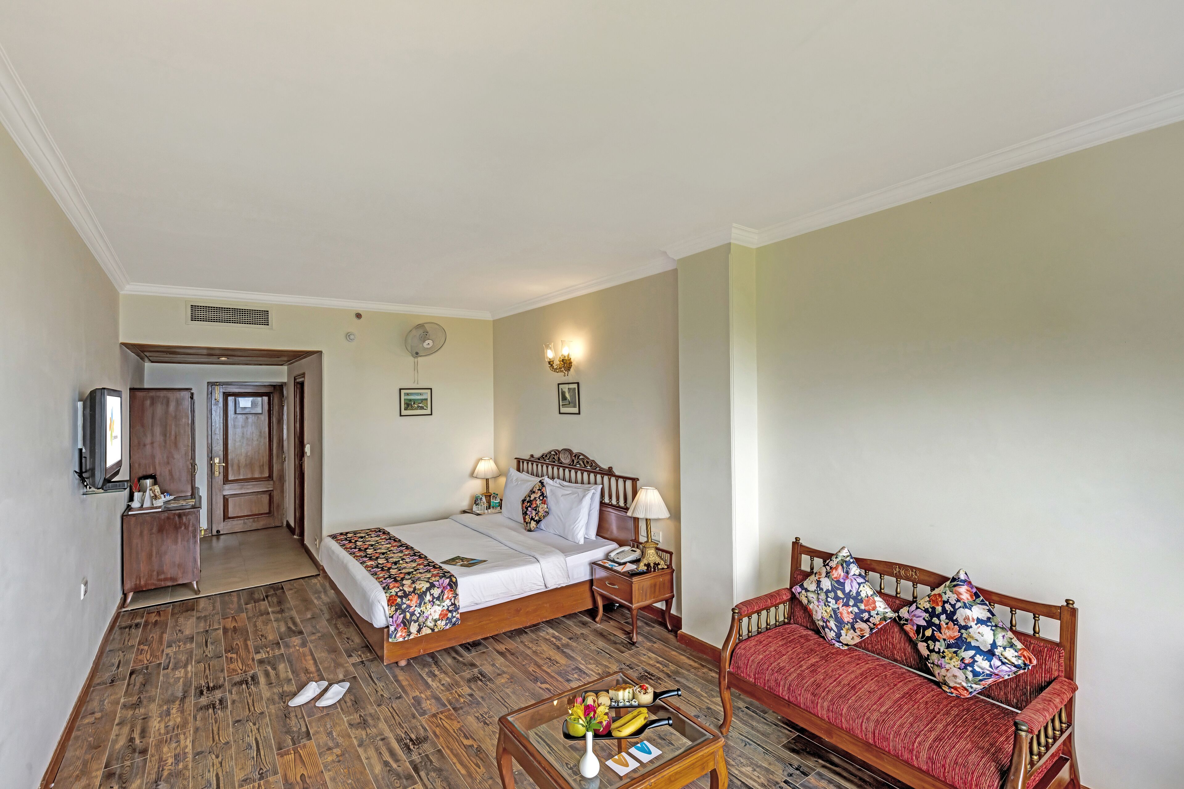 A hotel room with a bed, bedside table, lamp, and a sofa.