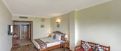 A hotel room with a bed, bedside table, lamp, and a sofa.