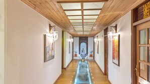 A long hallway with wooden ceiling beams, framed pictures on the walls, and a central water feature. - Club Mahindra Mashobra (Shimla)