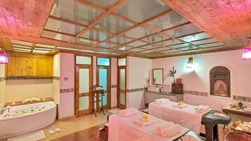 Relax in this serene spa room featuring a bathtub and two massage tables.