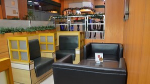 A seating area with booths and tables, featuring a Christmas garland and a menu on the table. - Hotel Sogo Dau (Mabalacat City)
