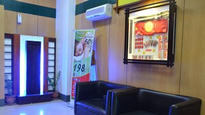 A lobby with a black leather sofa, a massage promo sign, and a display of red items. - Hotel Sogo Dau (Mabalacat City)