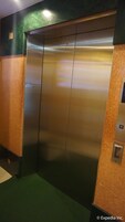 A metallic elevator with a green and brown wall.